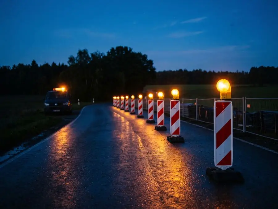 Baustellenabsicherung bei Dämmerung mit leuchtenden Warnlampen auf den Leitbaken