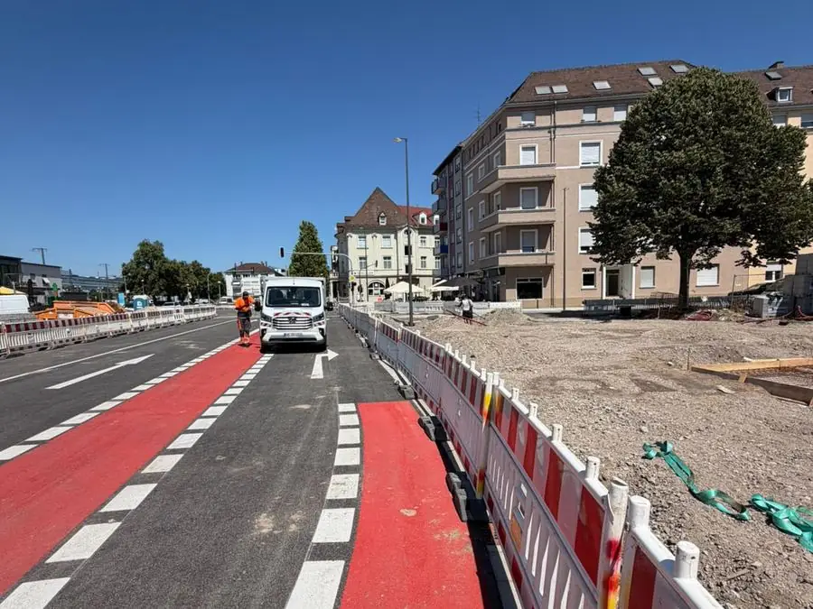 Abgesicherte innerstädtische Baustelle mit Absperrgittern entlang eines rot markierten Radwegs